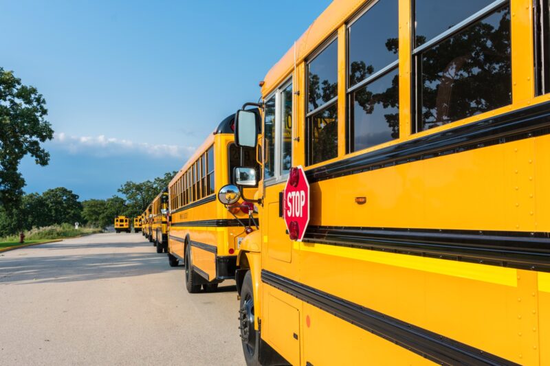Long line of yellow school buses lined up at a school campus
