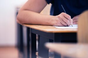 Student writing final exam in classroom.