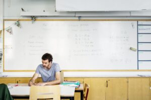 Teacher sitting by desk