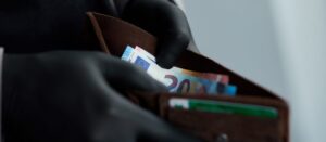 Man holding a wallet with money euro in hand in black medical gloves.