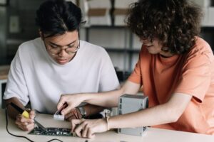 Two Friends Secondary School Students soldering together electronics circuit board