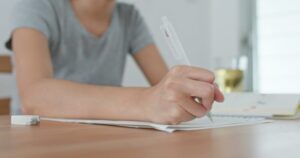 Woman take note on paper at home