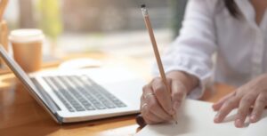 Close up of a woman writer hand writing in a notebook at home.