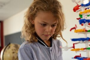 Close-up of a mixed -race schoolgirl looking at a DNA model in classroom at elementary school