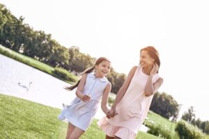 Single parent, Mother and daughter walking on a grassy field hol