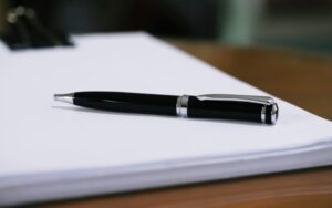 Black pen on pile of blank documents paper closeup blur background