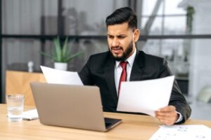 Disappointment stressed indian or arabian business man, sit at work desk with laptop in modern