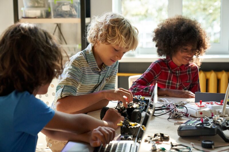 Diverse schoolkids building robotic technologies at STEM educational class.