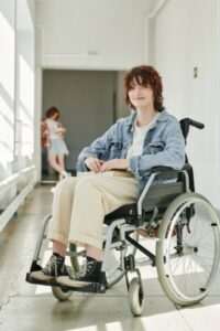 Happy teenage student with physical disability sitting in wheelchair