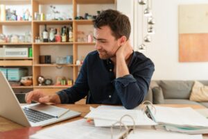 Man with laptop looking at paperwork