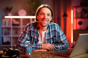 Attractive man sitting at desk with hands crossed on the chest and looking at camera.