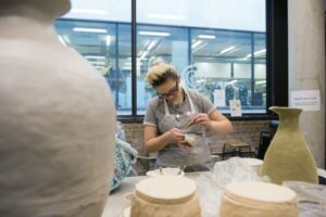 Woman in art studio glazing pottery