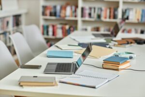 Background image of work table in college library with laptops and notes