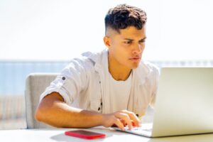 Happy argentinian student sinning with laptop outdoors and looking glad