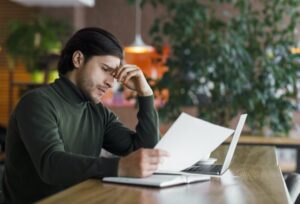 Young sad businessman having troubles with documents