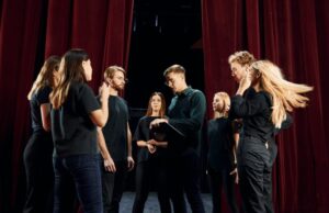 Group of actors in dark colored clothes on rehearsal in the theater