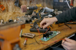 Close up of electrician hands checks the electrical voltage on the circuit board with a device