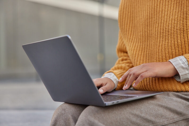 Cropped shot of unrecognizable woman freelancer earns money online uses application on laptop comput