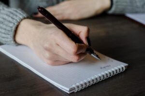 Notebook and pen. Girl holding pen.
