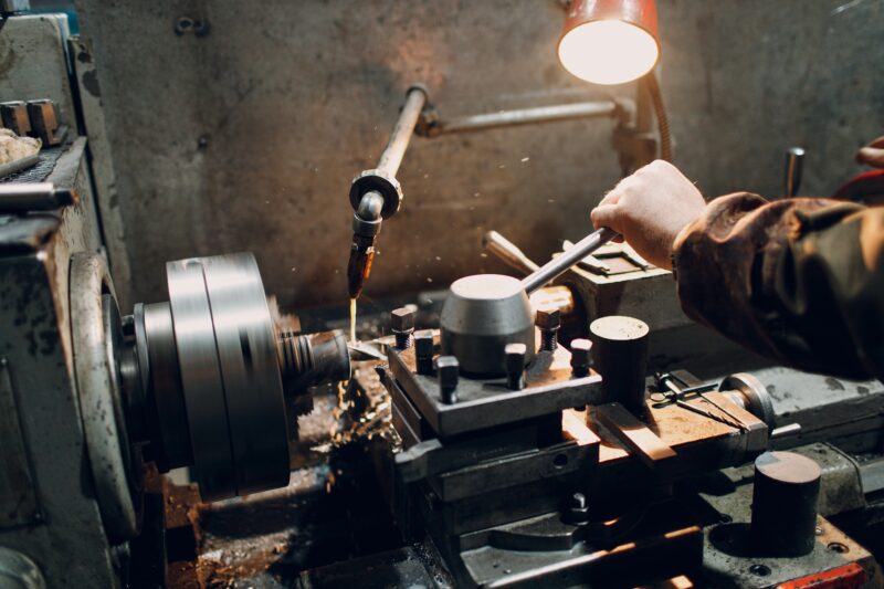Turner worker working on old lathe machine at factory