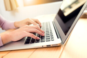 Woman typing report on notebok computer
