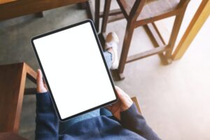 A woman holding black tablet pc with blank white screen while sitting in cafe