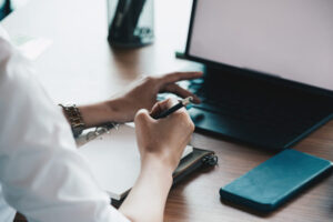 Cropped of woman hand taking notes with laptop at the table office