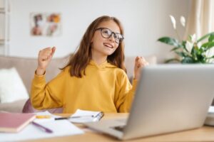 Glad girl in eyeglasses making yes hand gesture
