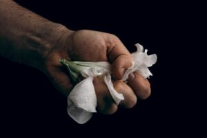 hand crumpling white fragile flower, metaphor of violence abuse aggression