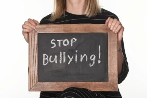 cropped view of girl holding chalkboard in wooden frame with stop bullying lettering isolated on