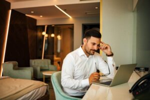 Troubled businessman looking at laptop computer in a hotel room.