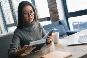 Attractive businesswoman looking at her notes in notebook while sitting at coworking desktop