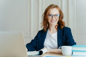 Glad smiling red haired young female concentrated on creating new business project