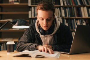 Student in casual clothes preparing exams late evening in library