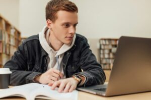 University student with ginger hair sitting at a desk.