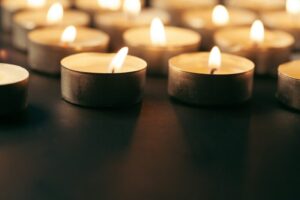 Burning candle on table in darkness, space for text. Funeral symbol