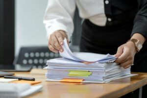 Businesswoman hands working in Stacks of paper files for searching document on folders papers.