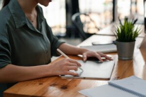 Close up of a woman holding a pen with a tablet at the office.