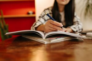 Close-up shot of woman taking notes with pen in book
