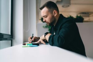 Focused man taking notes at workplace