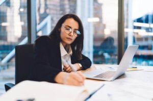 Focused woman writing in planner with pen at table