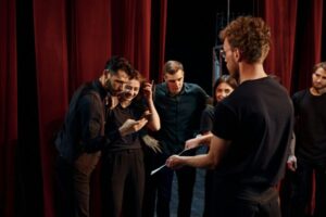 Group of actors in dark colored clothes on rehearsal in the theater