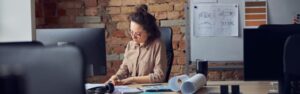 Professional female interior designer looking at blueprint while working on new design project