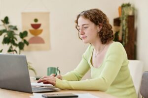 Young confident businesswoman making notes while working in front of laptop