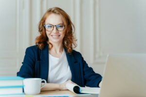 Glad smiling red haired young female concentrated on creating new business project