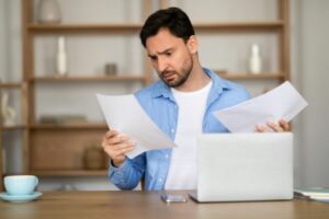 Man Evaluating Documents With Concern at His Workstation