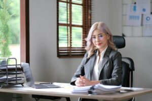 Charming young Asian woman wearing glasses holding a pen notebook laptop at the office.