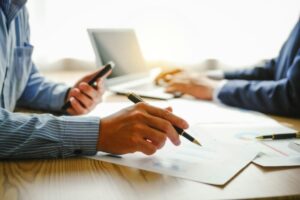 Desk-bound businessman calculates figures, verified accounts, and collaborates in discussions.