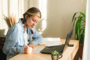 teenage girl sitting at desk and doing lessons. Student girl performing literature assignment