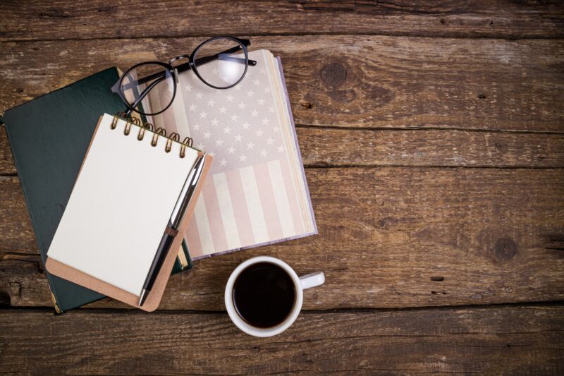 Office desk table with coffee cup, american history book, pen, notebook and eyeglasses